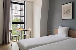 A hotel room with a bed, a table with breakfast, a chair, a window with curtains, and a framed picture on the wall. - Appart'City Confort Strasbourg Centre (Strasbourg)