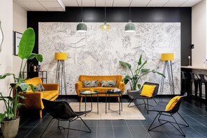 A modern living room with a sofa, chairs, a coffee table, and a large plant. - Appart'City Confort Strasbourg Centre (Strasbourg)