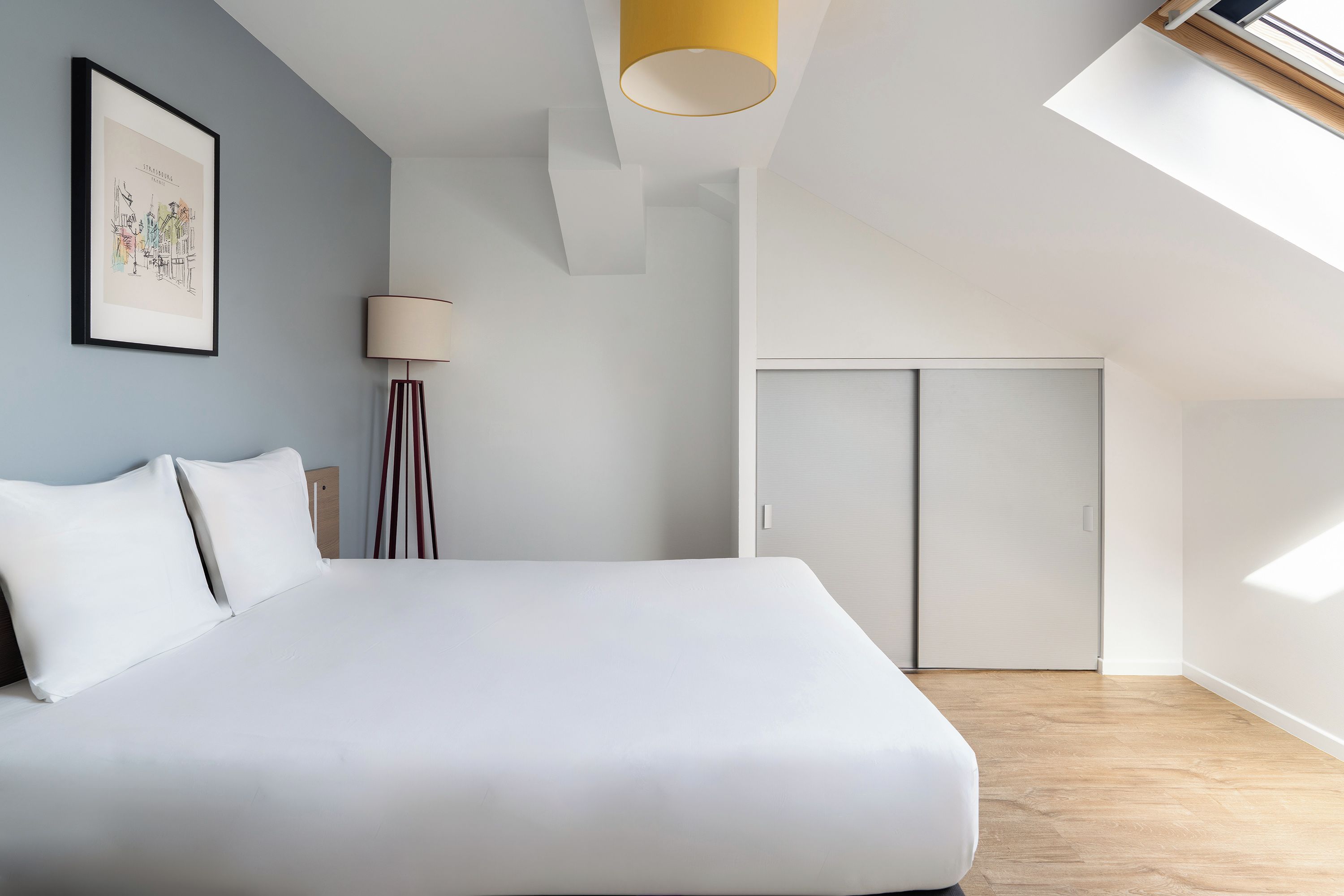 Ein modernes Schlafzimmer mit einem großen Bett, einer Stehlampe, einem Oberlicht und einer Tür.