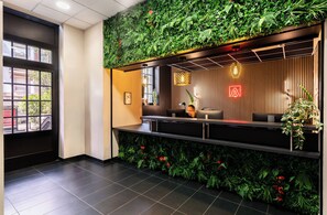 A reception area with a green wall, a reception desk, and a window. - Appart'City Confort Strasbourg Centre (Strasbourg)