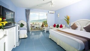 A hotel room with a bed, a TV, a balcony with a table and chairs, and a view of the sea. - Nomads Chalong Beach, Phuket (Rawai)