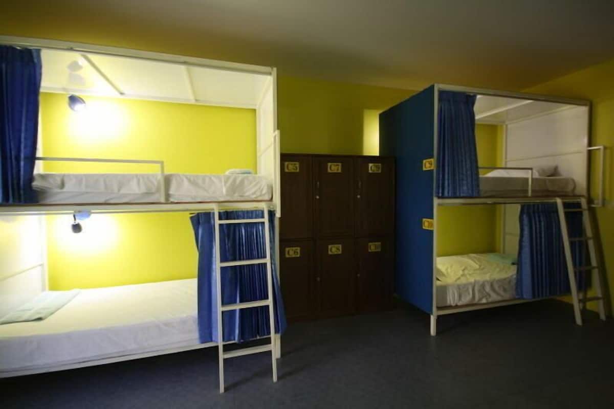 Une chambre de dortoir avec des lits superposés, une armoire et une échelle.
