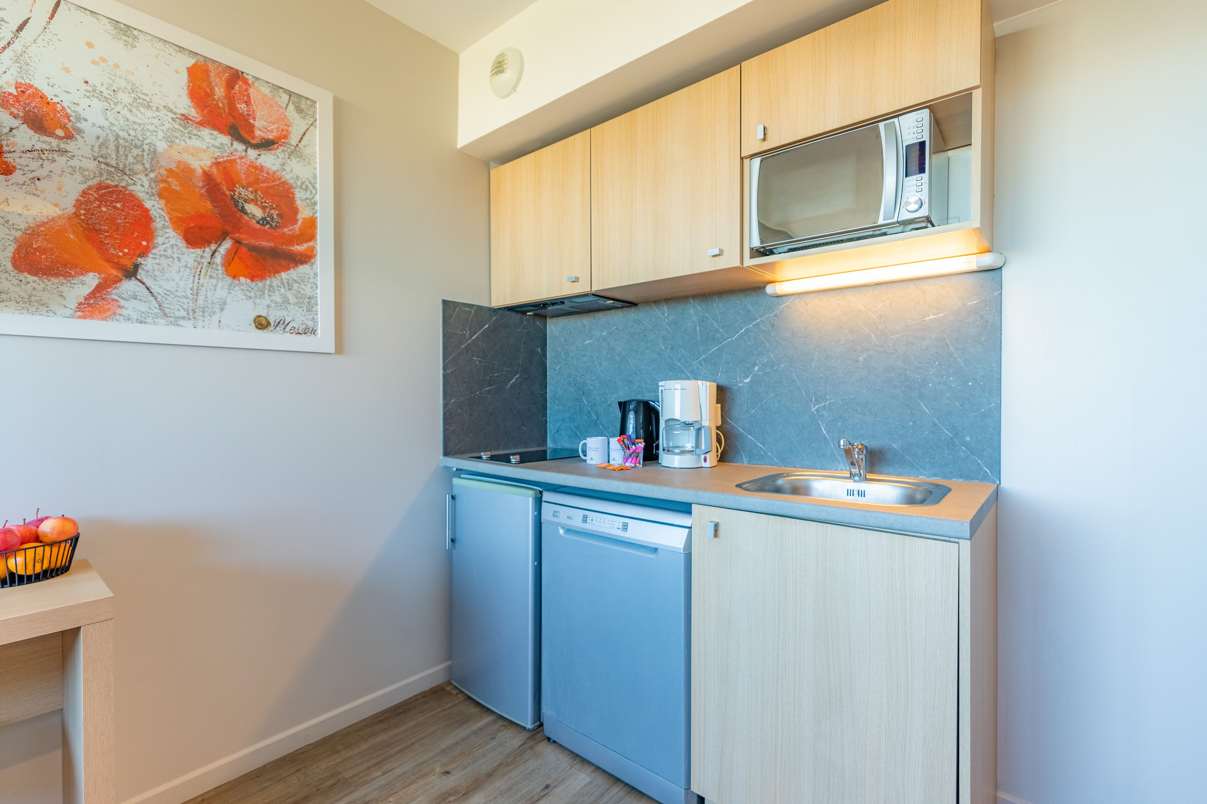 A compact kitchen with a microwave, coffee maker, and dishwasher.