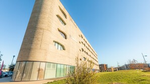 A modern building with a curved facade, multiple windows, and a clear sky.