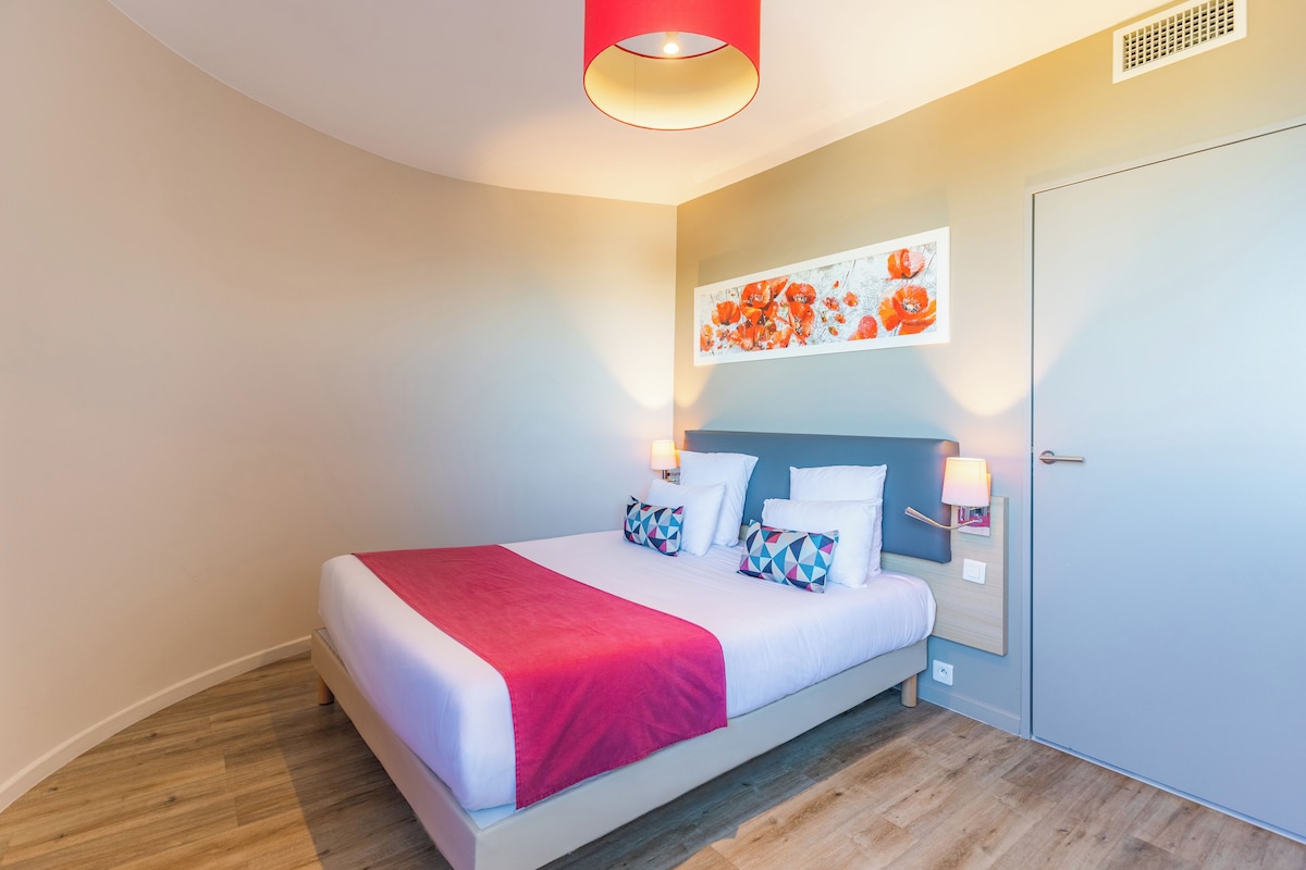 Ein modernes Schlafzimmer mit einem Bett, einer roten Akzentwand und einem Gemälde.