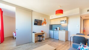 A modern apartment with a kitchen, dining area, and a small office space.