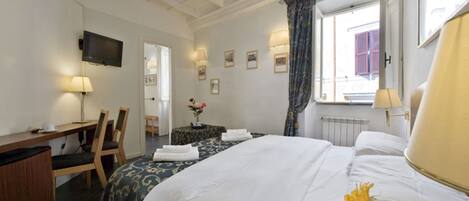 Hotelkamer met een bed, bureau, stoel, televisie en raam met gordijnen.