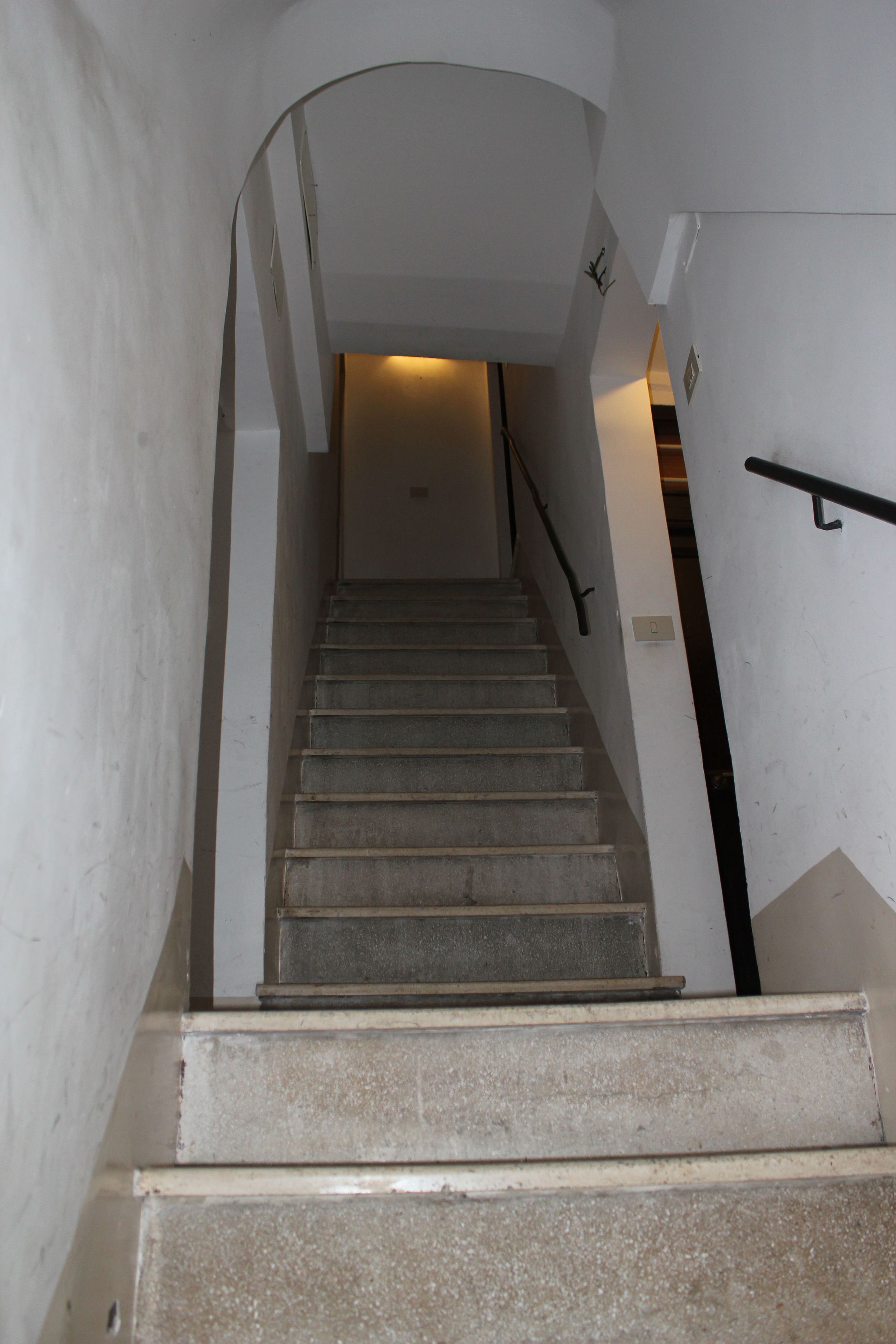 A staircase with a handrail, leading to an upper floor.