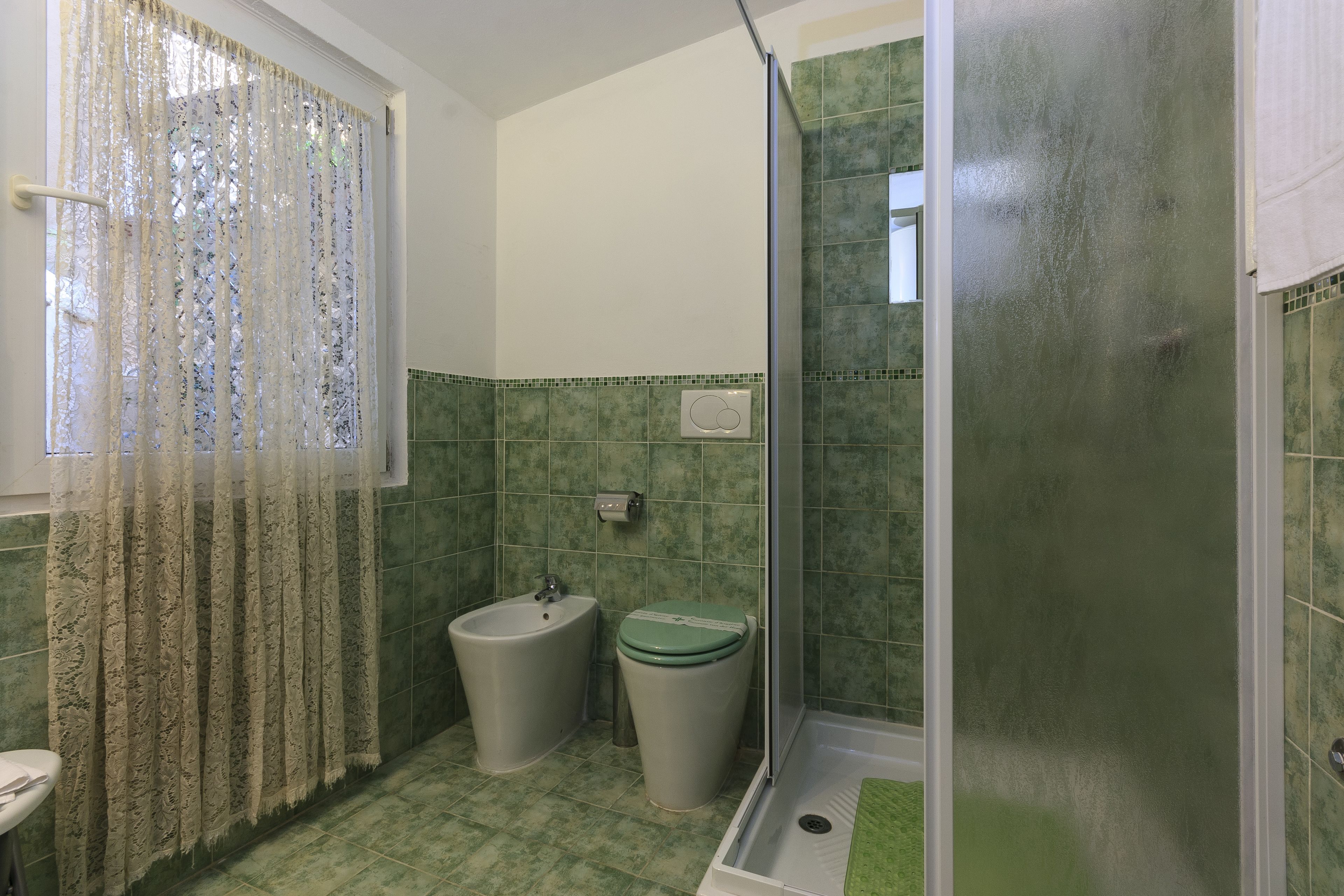 A bathroom with a shower, toilet, and bidet.