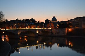 Vista nocturna de un río con un puente y edificios, incluyendo una estructura en forma de cúpula destacada.