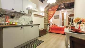 A compact kitchen with white cabinets, a tiled backsplash, and a wooden ceiling.