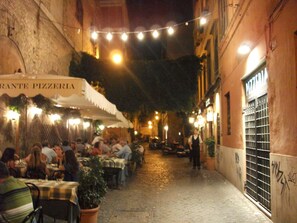 Una estrecha calle empedrada bordeada por mesas al aire libre de un restaurante.