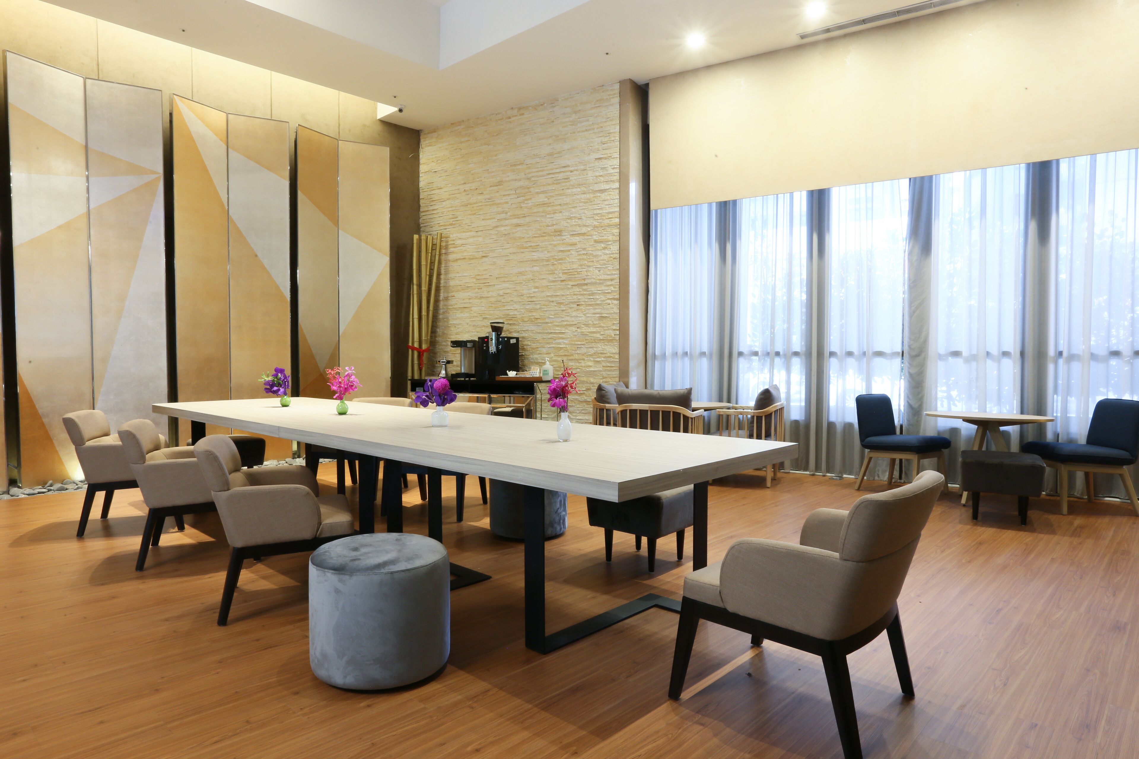 A modern conference room with a long table, chairs, and a coffee machine.
