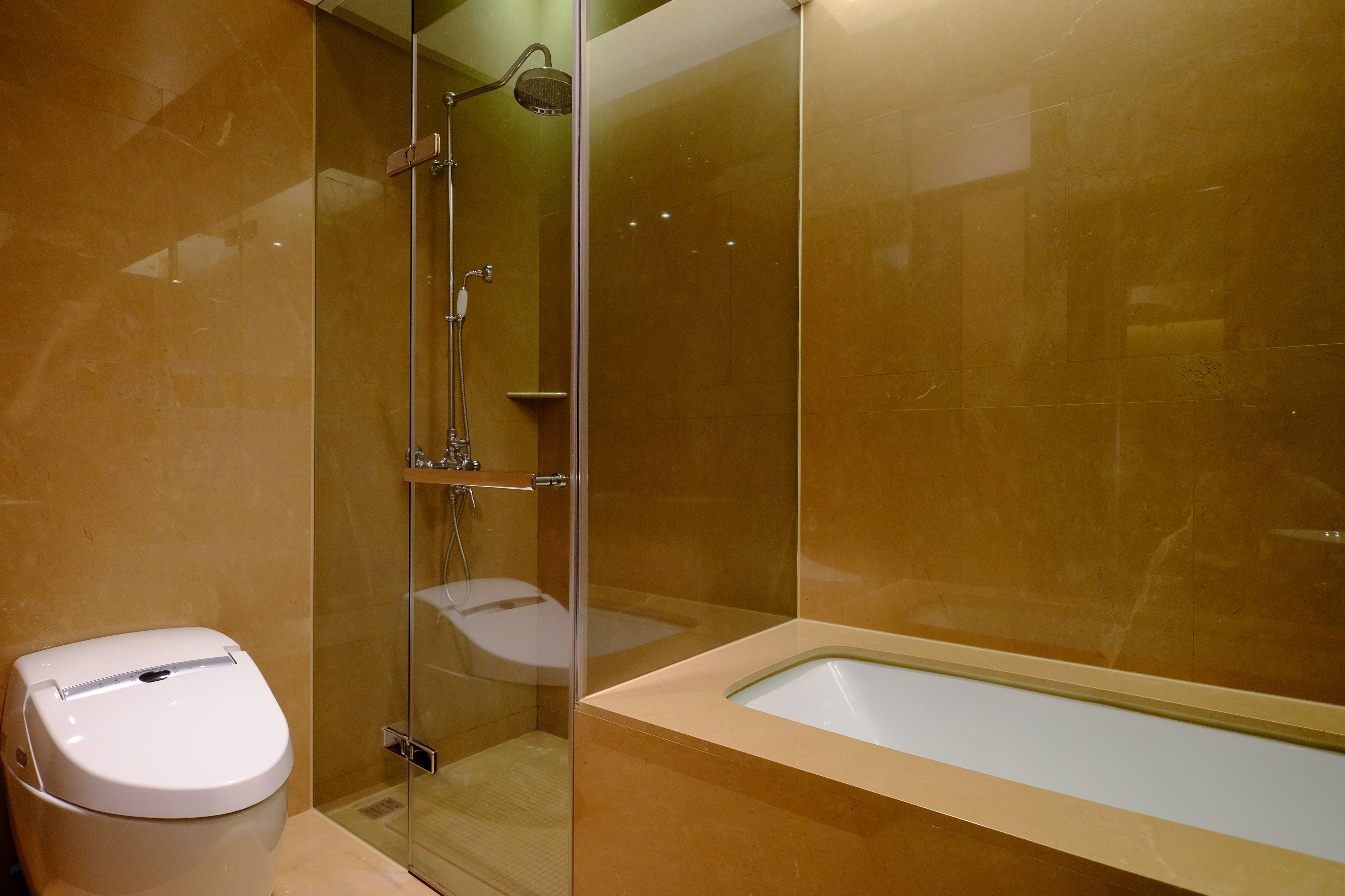 A modern bathroom with a glass-enclosed shower, a white toilet, and a bathtub.