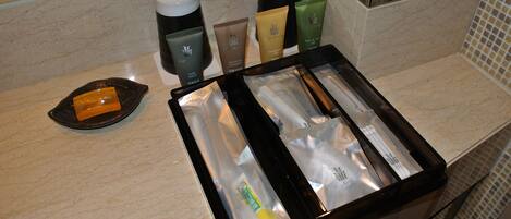 A bathroom counter with toiletries including a soap dish, a container of lotion, and a tray with various personal care items.