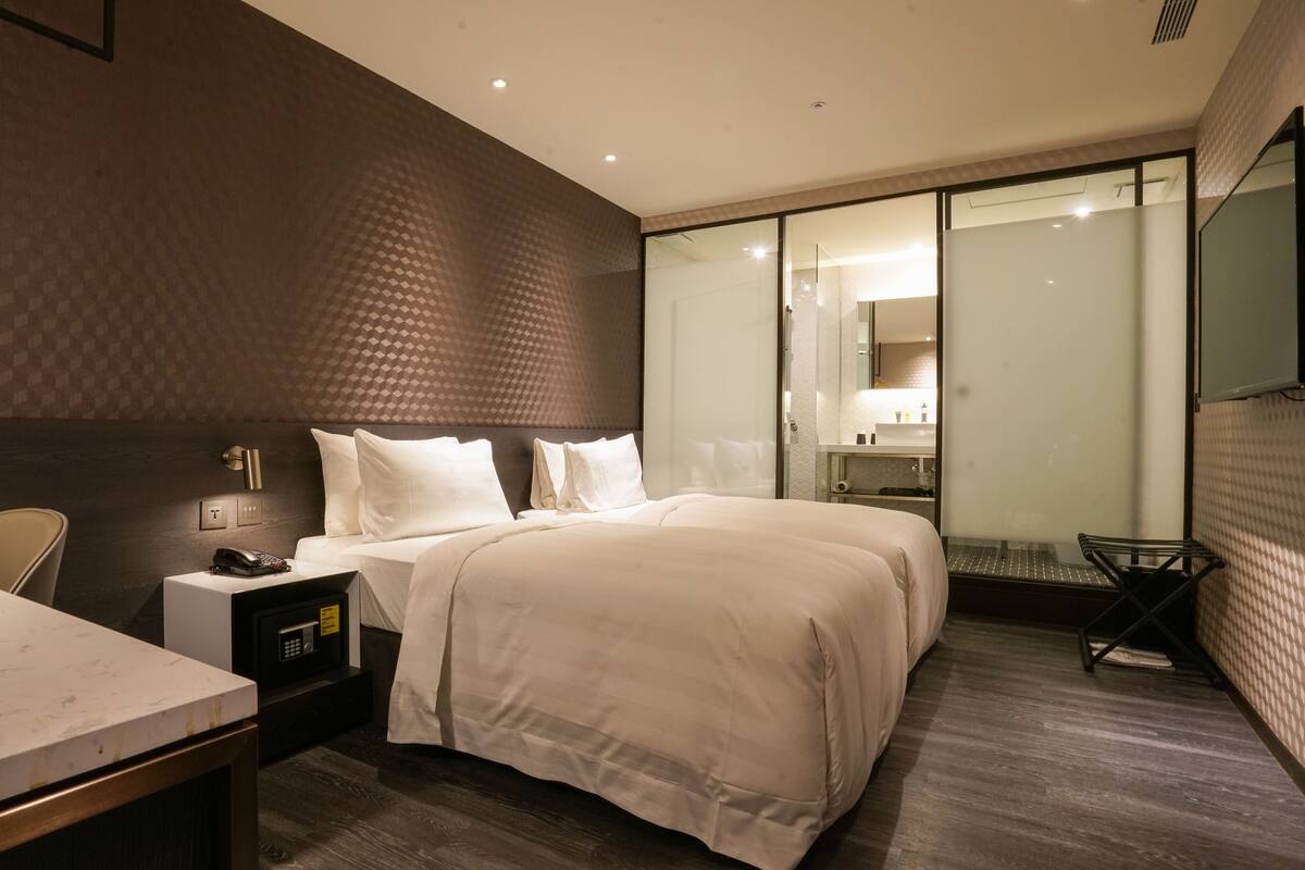 Ein modernes Hotelzimmer mit einem großen Bett, einem Nachttisch und einem Schreibtisch mit Stuhl.