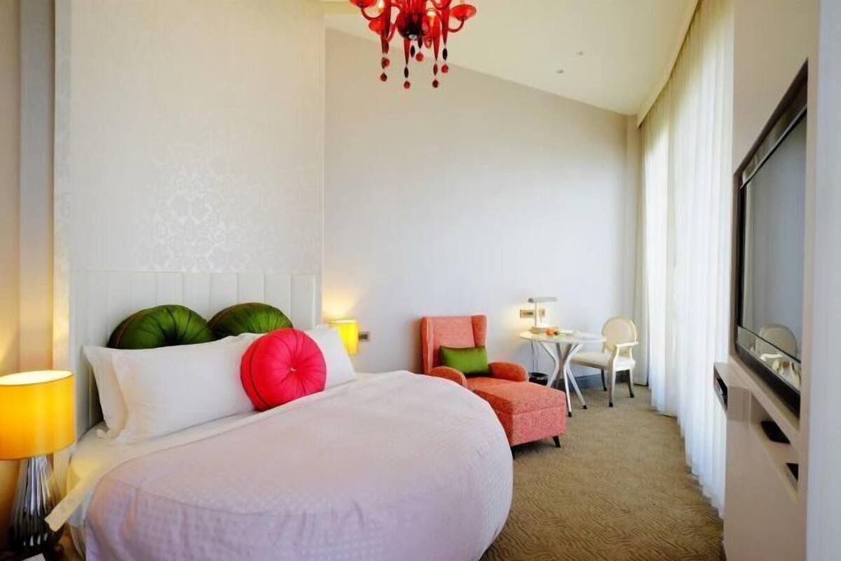 Ein Hotelzimmer mit Bett, Fernseher, Schreibtisch und Stuhl.