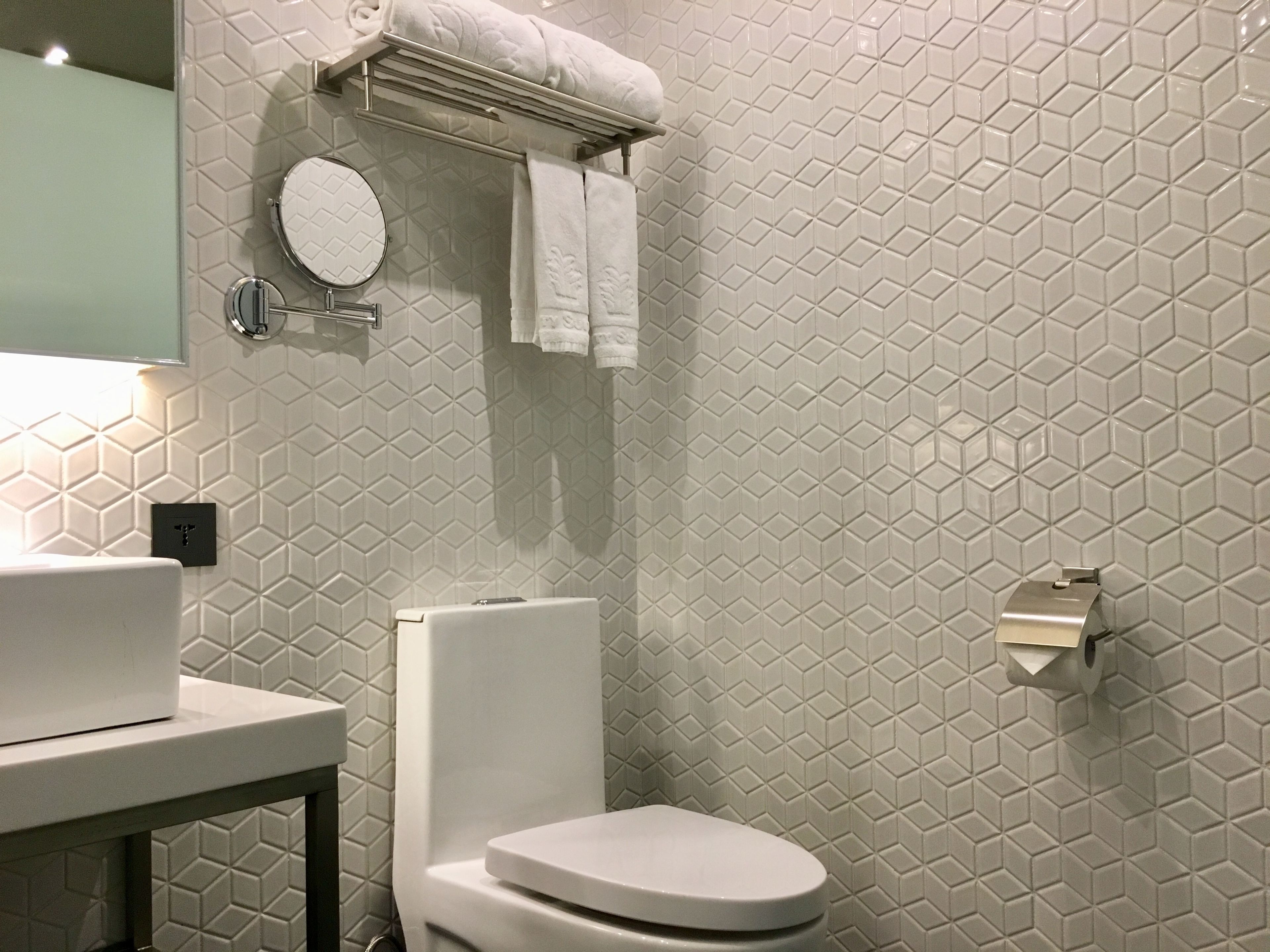 Een moderne badkamer met toilet, wastafel en handdoekhouder.