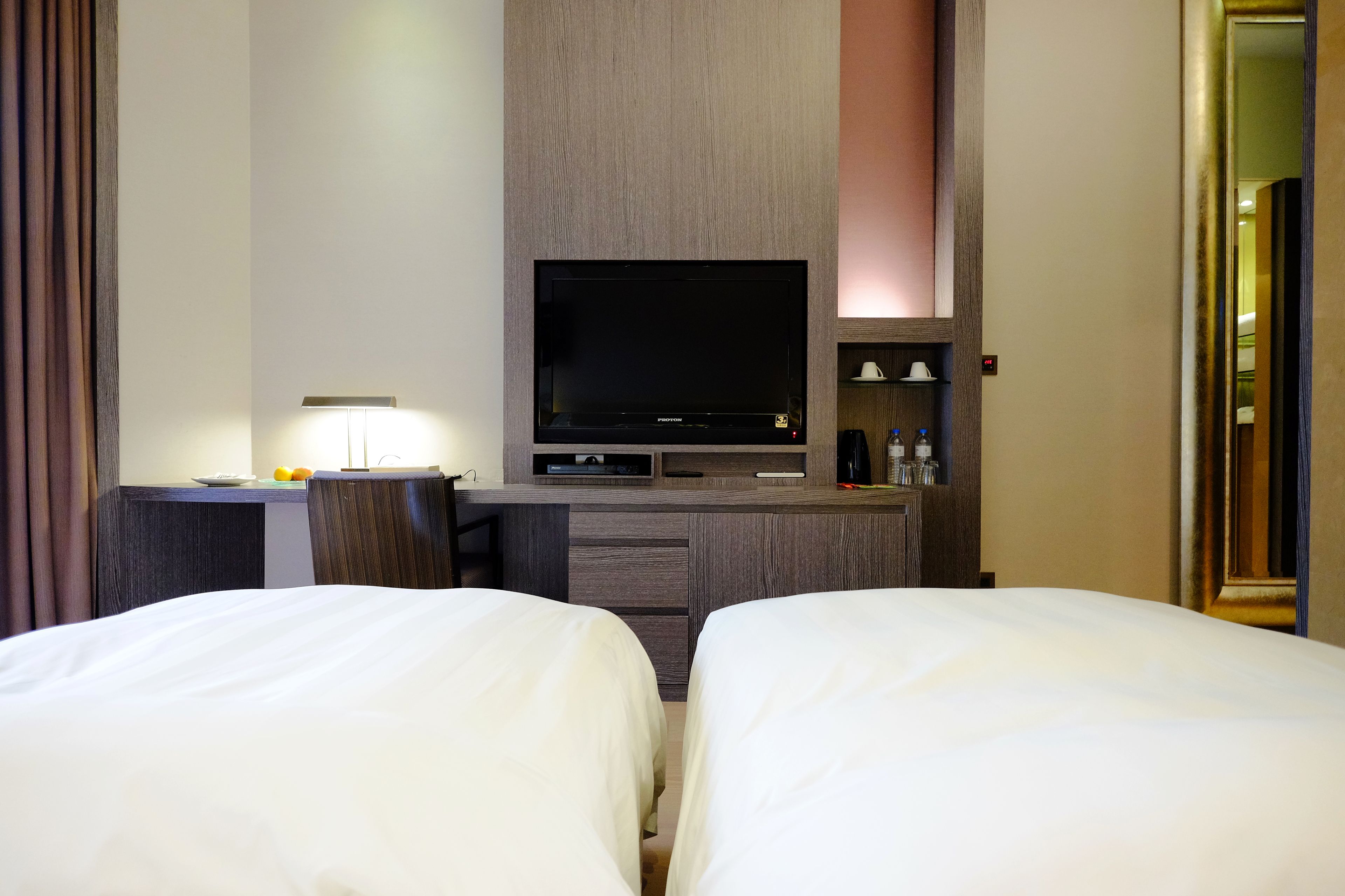 Une chambre d’hôtel avec deux lits, une télévision, un bureau avec une lampe et un mini-bar.