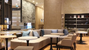 A modern lounge area with a curved sofa, round tables, and a bookshelf.