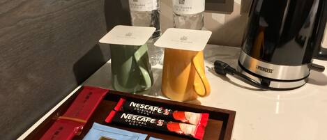 A tray with Nescafe Original and MIA The Original tea, two water bottles, and a black coffee maker.