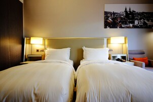 Een hotelkamer met twee bedden, nachtkastjes, een bureau en een stoel.
