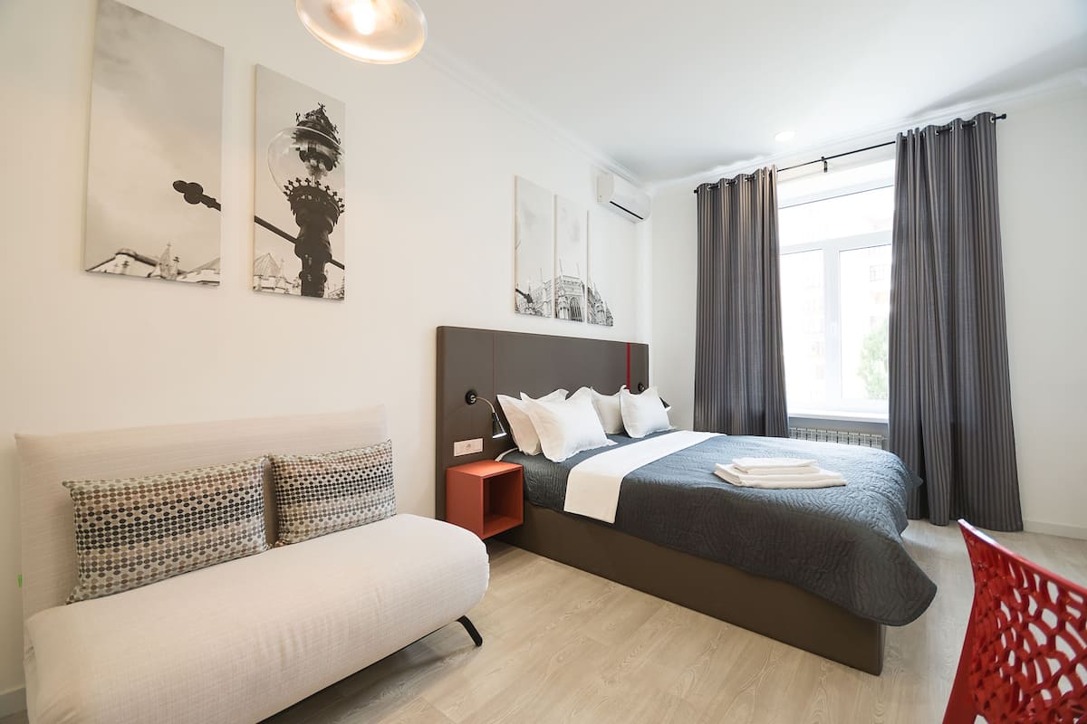 A modern bedroom with a bed, a sofa, and artwork on the walls.