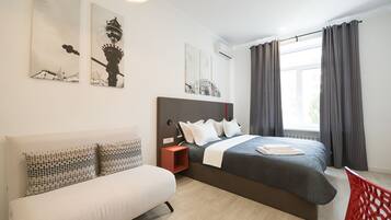 Ein modernes Schlafzimmer mit Bett, Sofa und Kunstwerken an den Wänden.