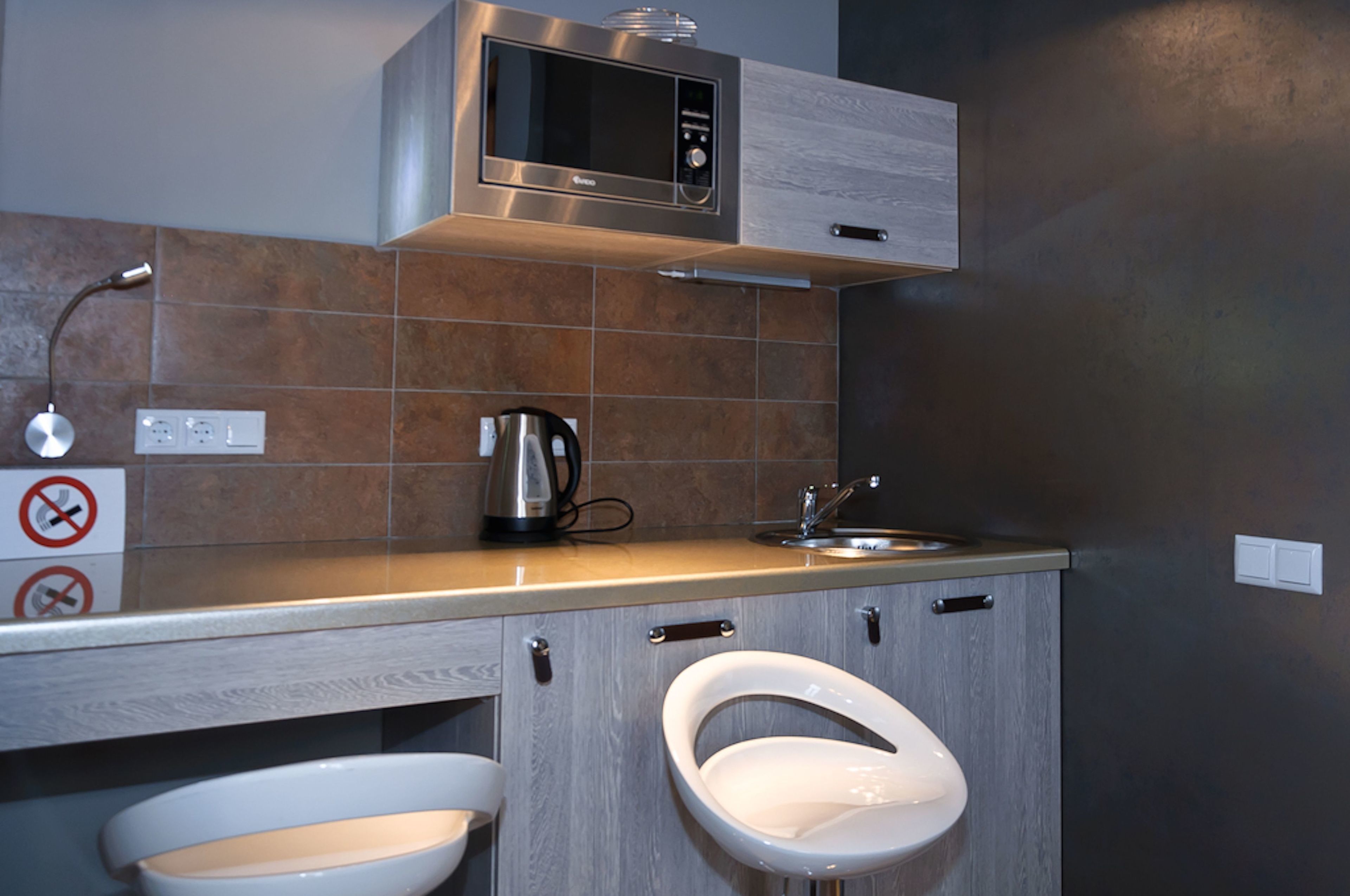 A compact kitchen with a microwave, kettle, and sink.