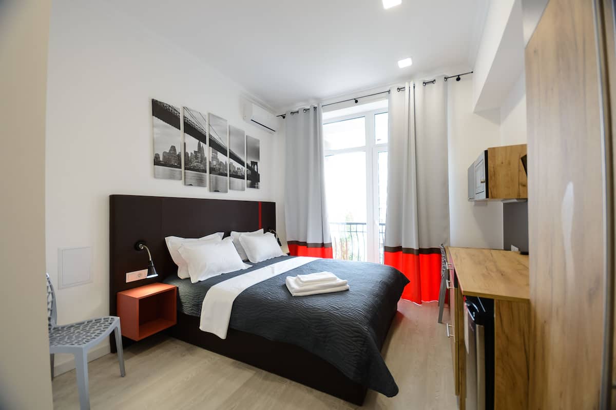 A modern hotel room with a large bed, a desk, and a chair.