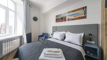 Een hotelkamer met een groot bed, een nachtkastje, een stoel en kunst aan de muur.