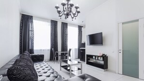 A modern living room with a leather sofa, a glass coffee table, and a chandelier. - Partner Guest House Khreschatyk (Kyiv)