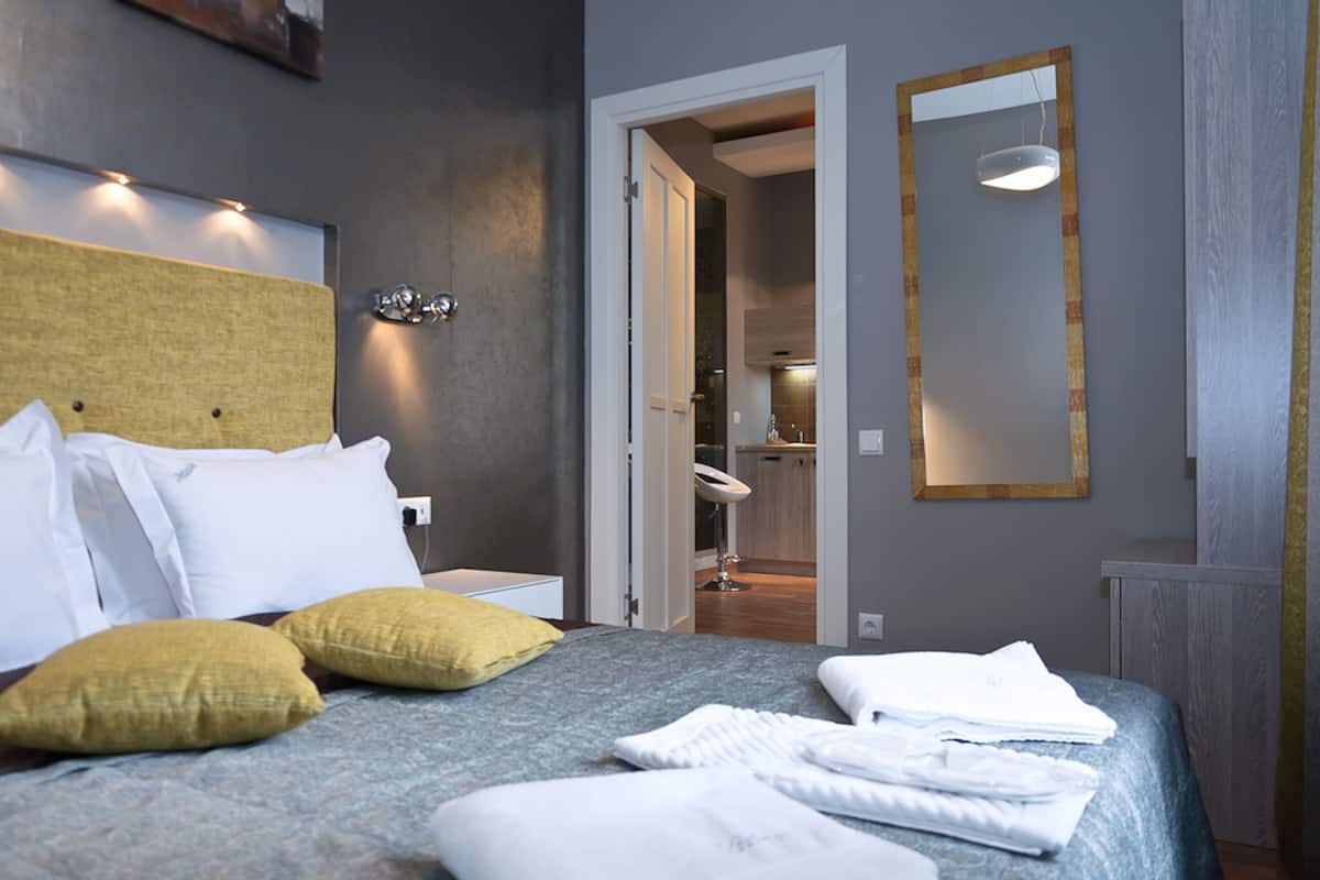 A neatly made bed with pillows, a bedside table, and a mirror on the wall.