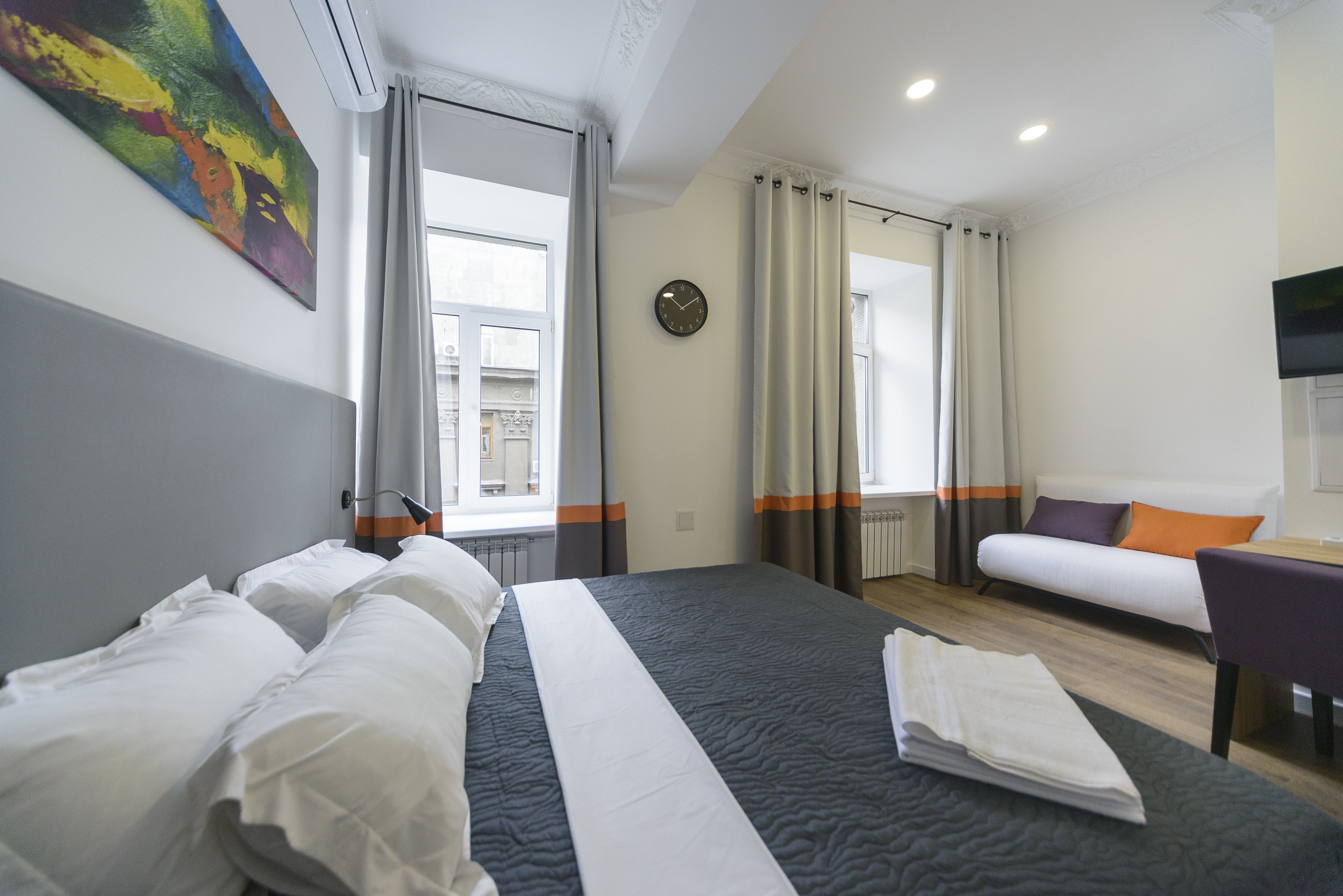Una habitación de hotel con una cama grande, un sofá, un escritorio y una ventana con cortinas.
