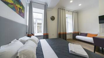 Una habitación de hotel con una cama grande, un sofá, un escritorio y una ventana con cortinas.