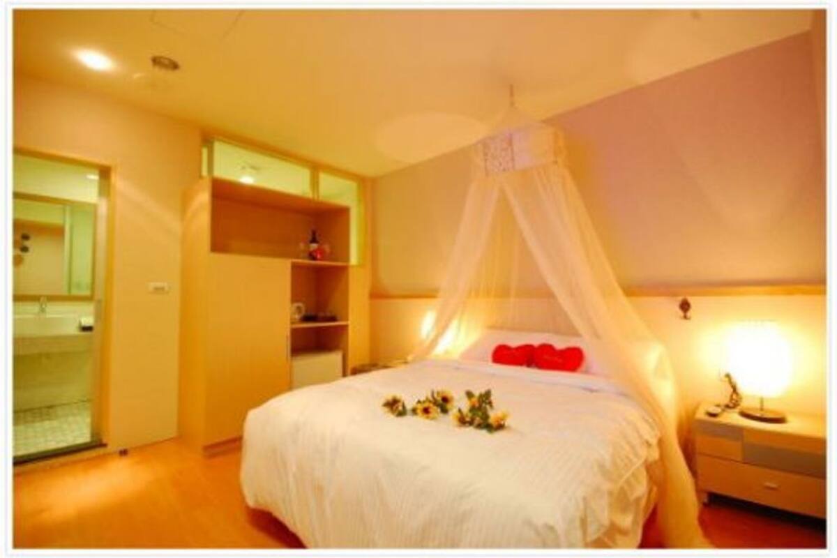 Een slaapkamer met een hemelbed, nachtkastjes en een kledingkast.