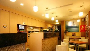 A restaurant interior with a counter, seating area, and a television screen. - Tanxiang Resort Hotel Sun Moon Lake (Yuchi)