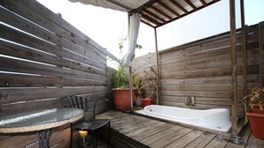 A wooden deck with a round table and chairs, a small black chair, a white bathtub, and several potted plants. - Tanxiang Resort Hotel Sun Moon Lake (Yuchi)