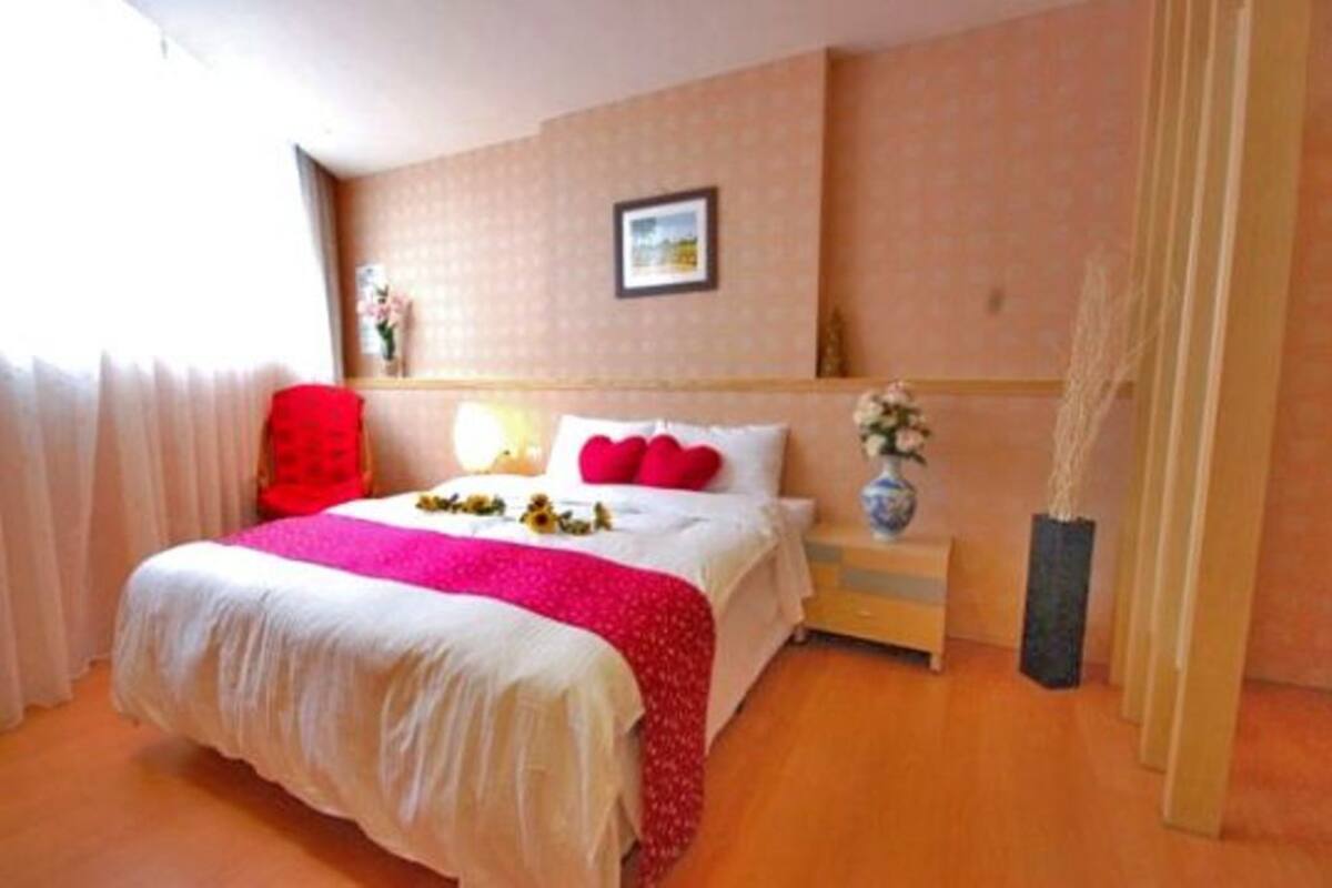 Een hotelkamer met een bed, een nachtkastje, een vaas met bloemen en een schilderij aan de muur.