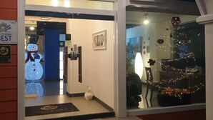 A hotel entrance with a glass door, a snowman decoration outside, and a Christmas tree inside.