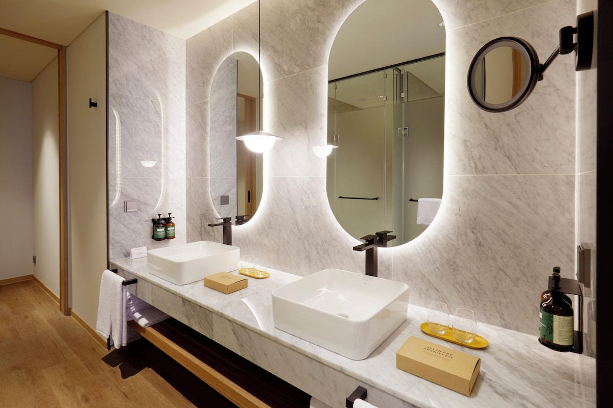 A modern bathroom with two sinks, large mirrors, and a shower.