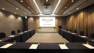 A conference room with a large screen displaying 'VOCO AN IHG HOTEL Seoul Gangnam'.