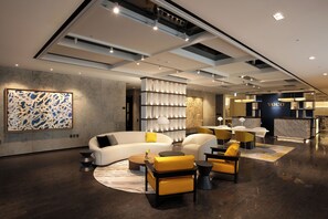 A modern hotel lobby with a white sofa, yellow chairs, and a marble reception desk. - voco Seoul Gangnam by IHG (Seoul)