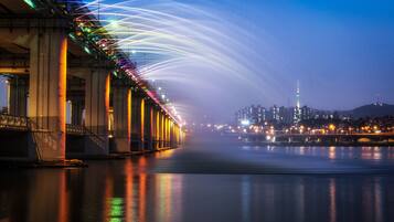 A bridge with illuminated lights and a city skyline in the background.