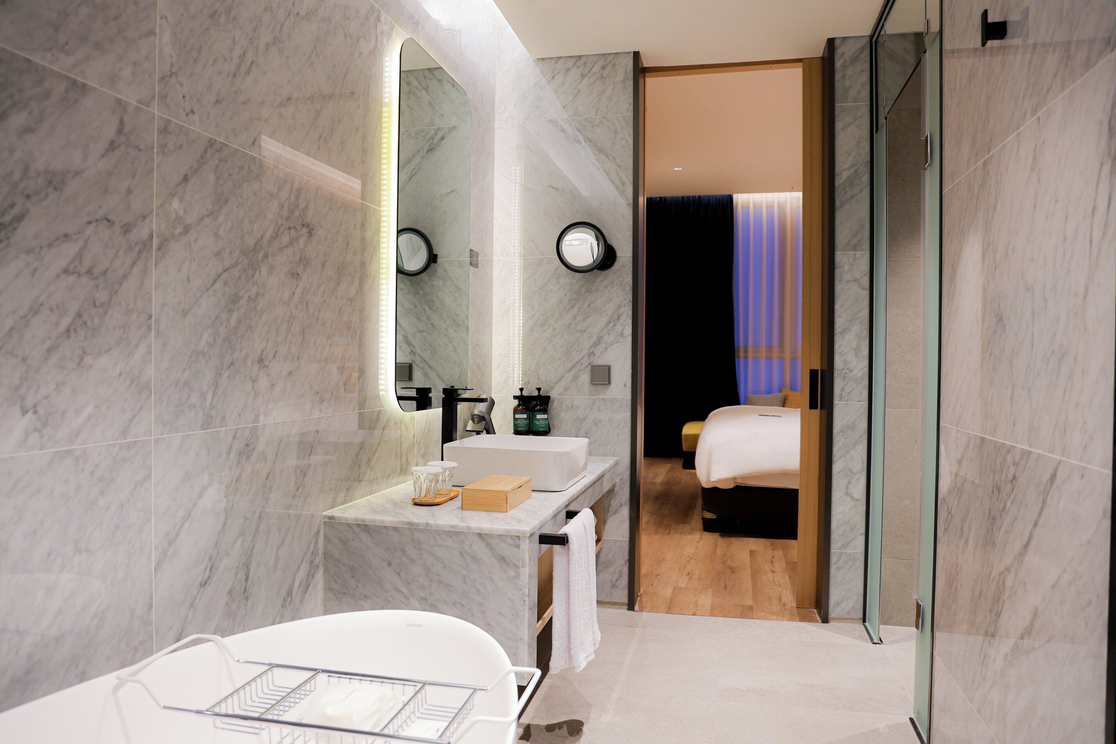 Un baño moderno con lavamanos de mármol, un espejo grande y una cabina de ducha de vidrio.