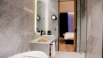 Un baño moderno con lavamanos de mármol, un espejo grande y una cabina de ducha de vidrio.
