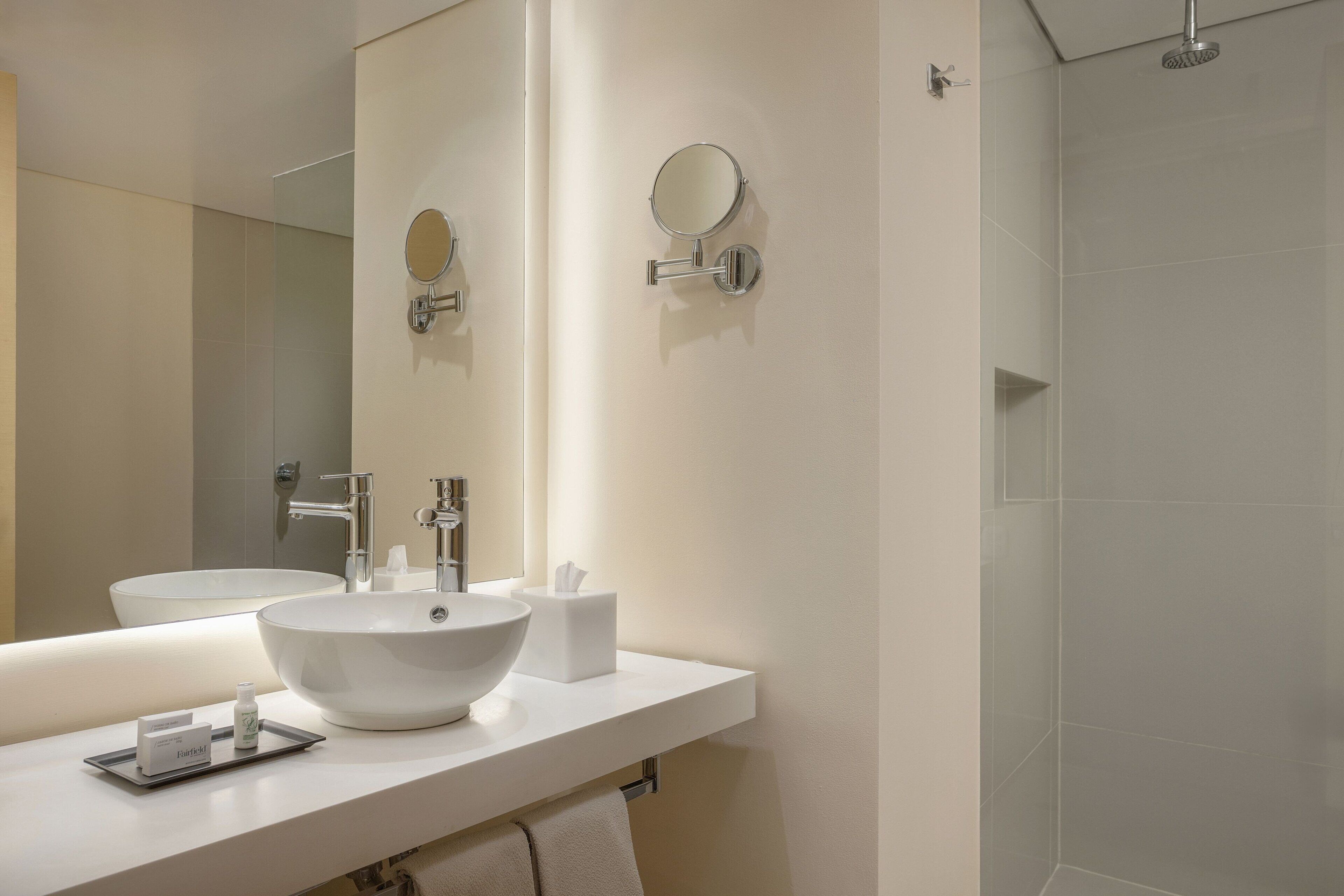 Un baño moderno con un espejo grande, un lavabo y una ducha.