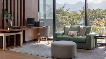 Een moderne woonkamer met een bureau, een groene bank en uitzicht op bergen.