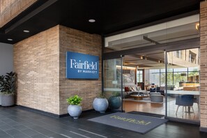 A Fairfield by Marriott hotel entrance with a modern design, featuring a brick facade, large windows, and a welcoming reception area.