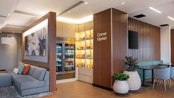 A modern interior with a seating area, a refrigerator stocked with snacks, and a sign reading "Corner Market".